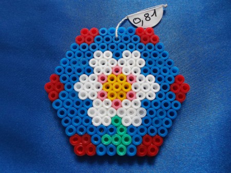 Fleur dans hexagone - 7,3 cm de largeur sur 6,3 cm de hauteur - Prix : 0,81 euro