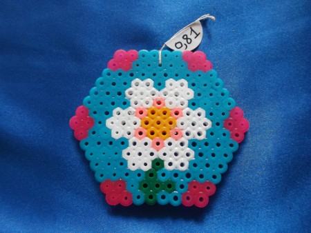 Fleur dans hexagone - 7,3 cm de largeur sur 6,3 cm de hauteur - Prix : 0,81 euro